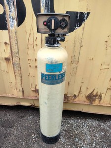 Residential water treatment tank labeled Peerless