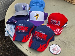 Lot of hats and a button including Hollister, Minnesota-themed caps, a USA cap, Fire First In Last Out hats, Trump and a 1987 Minnesota Twins World Champions button.