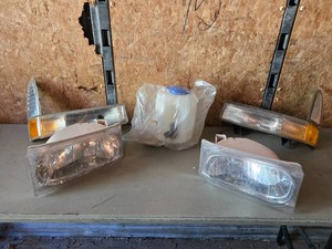 Lot of Automotive Parts including Headlights, Lamp Lenses, Fluid Reservoir, Hubcaps, and Door Handle