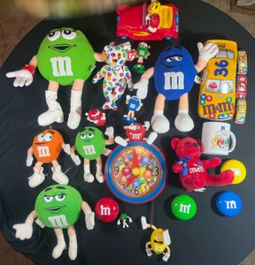 M&M Merch lot of 19  beanie baby, plushs, wall clock, Xmas bobble M&Ms, Tin, 3 cars, mug, m&m Easter candy dishes, porcelain car figurine-Clock missing back, batteries corroded, pieces untested, dirt dust some stitching wear in plushies