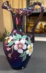 VINTAGE Signed Fenton hand-painted iridescent purple carnival glass pitcher featuring a ruffled crest rim and floral motif.
