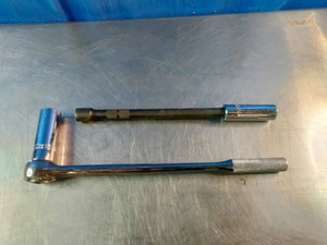 12 Socket wrench (ratchet) with a socket attached, alongside a metal socket extension bar