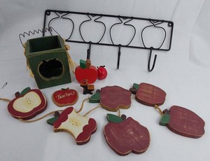 Apple-themed decorative assortment including a black metal wall rack, wooden birdhouse, apple