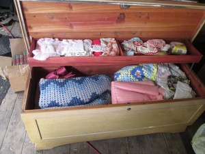 Lane cedar chest filled with blankets, one leg is cracked in the back