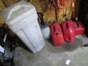 Brine tank with scrap wood, assorted size gas cans and chemical sprayer