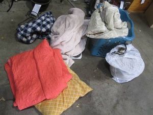 Laundry basket and bag with a variety of blankets and bed linens