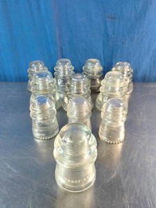 A collection of vintage clear glass telephone and telegraph line insulators, made by the Hemingray Glass Company