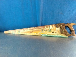 Vintage hand saw featuring a hand-painted winter folk art landscape scene on the metal blade,
