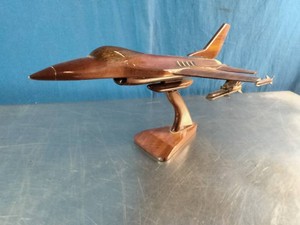 A handcrafted solid mahogany wood desk model of an F-16 Fighting Falcon fighter jet on a matching wooden display stand