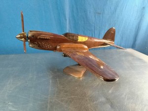 Ahandcrafted wooden desktop model of a Curtiss P-40 Warhawk fighter plane