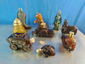 A collection of vintage Avon novelty cologne and aftershave decanters from the 1970s, shaped like various western, historical, and animal themes
