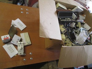 Box containing a large supply of electrical switches, timers and more
