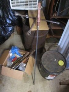 Corner lot containing a variety of varying head-style screwdrivers, 4-way tire iron, metal bucket of wood stain and other supplies shown