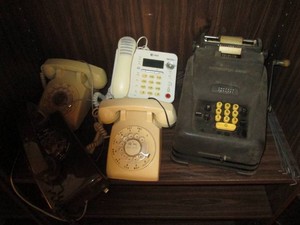 Antique Remington Rand adding machine with assorted vintage rotary and button-dial telephones