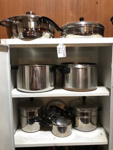 Pots and pans all on top of cabinet and 2 shelves