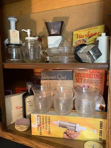 Pampered Chef, juicers, nut grinders, Kool Aid mugs all in cupboard
