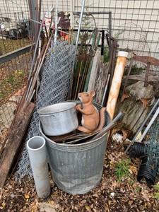 Large assortment of metal in cage and along house