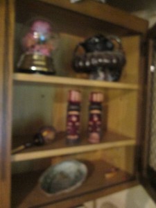 Vintage carved wood totems, sea shell heavy abstract pottery and other Vintage goodies shown in cupboard