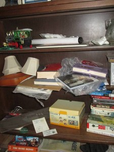 Content on shelves to include misc vintage Christmas ornaments, books, greeting cards, mini lamp shades, digital camera and more