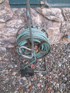 Vintage metal hose rolling reel with unknown length garden hose
