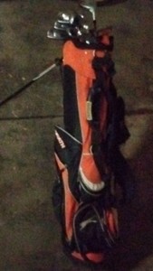 Orange and black golf bag with clubs