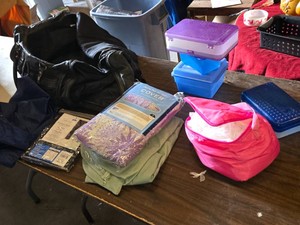 Lot of household items including ironing board cover, window panel, duffel bag, plastic storage containers, and pink bag with unknown contents
