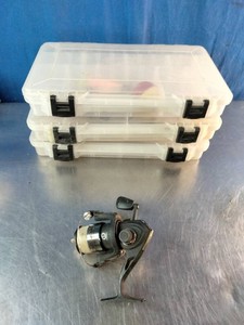 Set of three clear plastic utility boxes (resembling standard Plano StowAway Utility Boxes) and Shakespeare Crusader black open-face spinning fishing reel