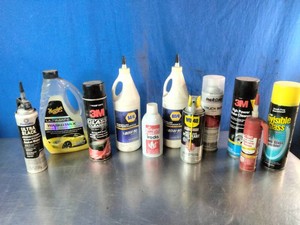 A collection of automotive fluids, sealants, and cleaning supplies on a metal surface.