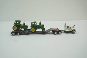 Mac semi tractor with flat bed implement hauling trailer loaded with 2 John Deere tractors 164 scale die cast metal