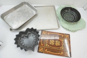 group of kitchenware including a large aluminum cookie sheet and cake pan, place mats, strainer, hot plate and more