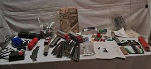 Model train lot with Santa Fe engines and various accessories including track, transformer, and scenery components. Includes multiple train cars, a tank car, a crossing gate, track pieces, and a hobby guide.