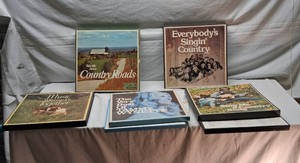Vinyl record album collection including titles like Take Me Home Country Roads, Everybodys Singin Country, and The Very Best Of Tammy Wynette