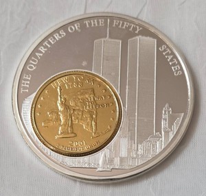 American Mint "The Quarters of the Fifty States" New York World Trade Center Commemorative Medallion featuring a gold-plated 2001 New York State quarter inlaid into a larger silver-plated medallion depicting the World Trade Center Twin Towers.