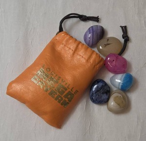 Orange faux glove leather drawstring pouch paired with a collection of tumbled, polished gemstones.  The pouch and gemstones come from Louisville Ky Mega Cavern.  Pouch is roughly 3 x 4.