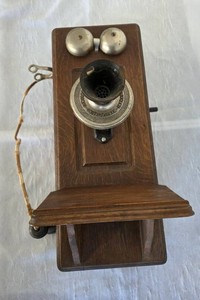 Antique 1913 Western Telephone Manufacturing Company wall telephone with hand crank. Wood Oak finish. The receiver is missing a collar.  The crank turns and creates a slight chime sound.  26" T x 13" W.  Very Heavy.