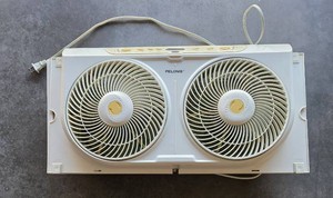 White PELONIS 9 (fan blades) twin window fan with top electronic control panel. Designed to fit standard window frames to pull in fresh air, exhaust stale air, or circulate air across rooms.