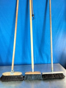 Three traditional wooden-handled floor and push brooms