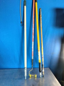 A collection of long-handled utility, painting, and maintenance poles,