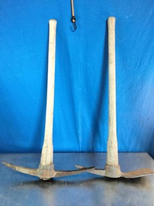 Two traditional heavy-duty digging and breaking tools, specifically a pickaxe