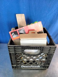 Plastic crate filled with a collection of used masonry, concrete finishing, and hand tools