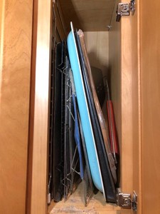 Baking dishes and metal mixing bowls all inside dishwasher and cupboard